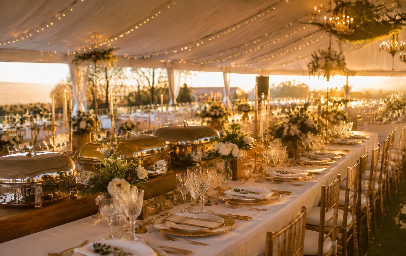 Elegant wedding reception set with gold chairs and chafing dishes